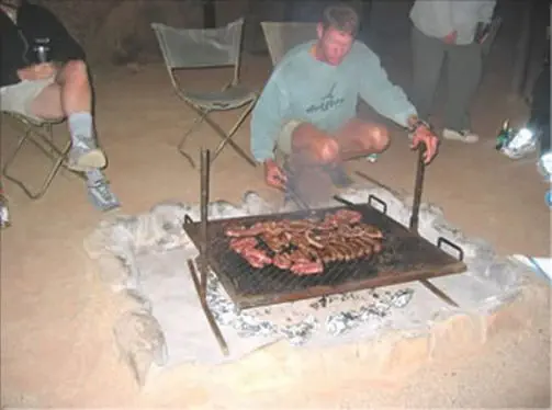 Nach einem erlebnisreichen Tag ist der beste Platz am Lagerfeuer, während Euer Guide Euch zeigt, wie' schmackhaft "Buschküche" sein kann...